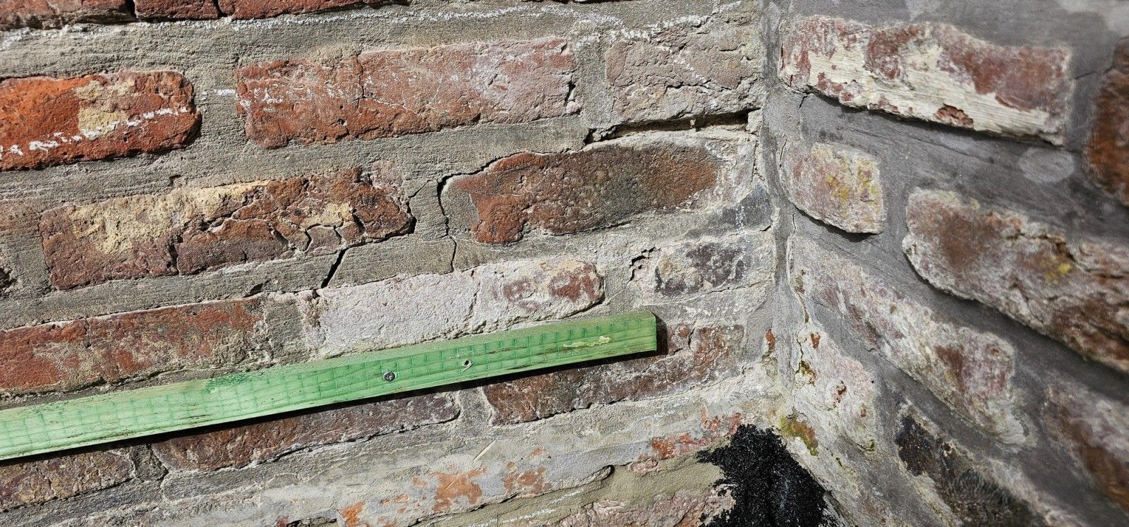 Détail d’une façade en briques fissurée à Beyne-Heusay, avec ouverture localisée d’un joint horizontal à proximité de l’angle du mur.