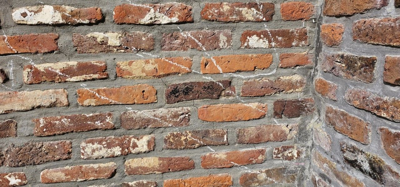 Vue générale de la zone fissurée d’une façade en briques à Beyne-Heusay, avec tracés de repérage matérialisant le cheminement des fissures.