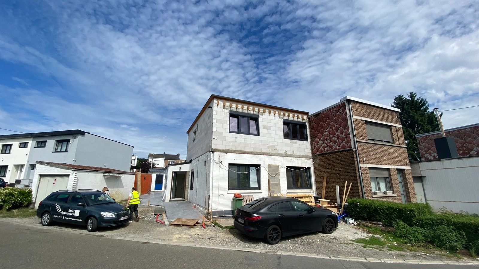 Maison en cours de rénovation énergétique à Herstal, avec étage surélevé, toiture plate et nouveaux châssis foncés installés.