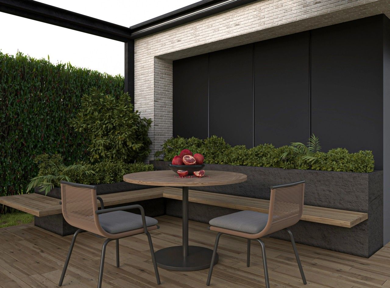 Espace repas extérieur d’une maison contemporaine à Juprelle, avec terrasse en bois, banquette intégrée, plantations et pergola noire.