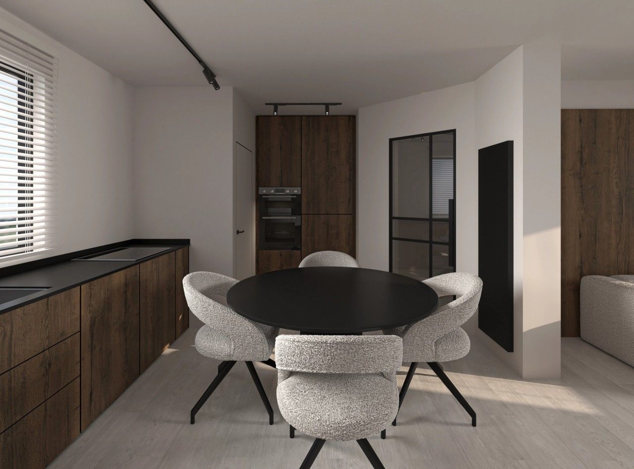 Vue de la salle à manger intégrée à la cuisine rénovée à Herstal, avec table ronde noire, mobilier en bois foncé et porte vitrée à cadre métallique noir.