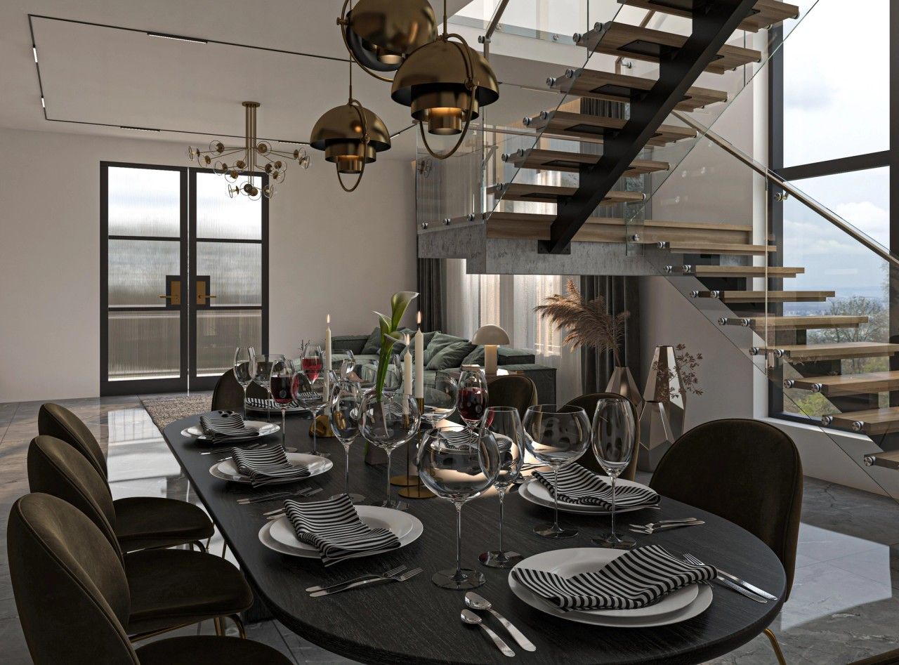 Vue rapprochée de la salle à manger d’un appartement contemporain à Verviers, avec grande table sombre, fauteuils aux accents dorés et escalier en bois et verre en arrière-plan.