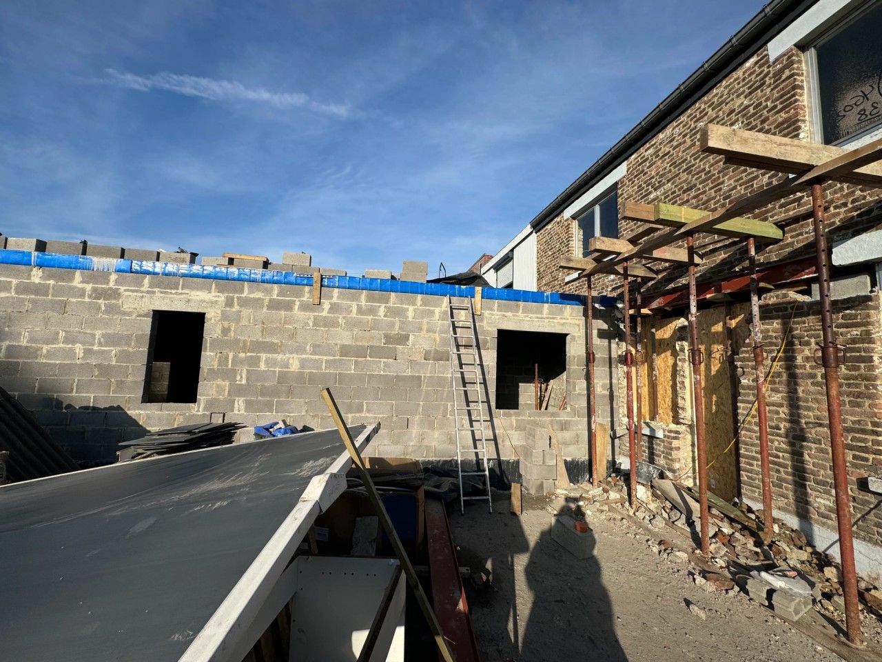Reconstruction de l’annexe arrière d’une maison à Visé, avec nouvelles maçonneries en blocs, ouvertures et étaiement contre le bâtiment existant.