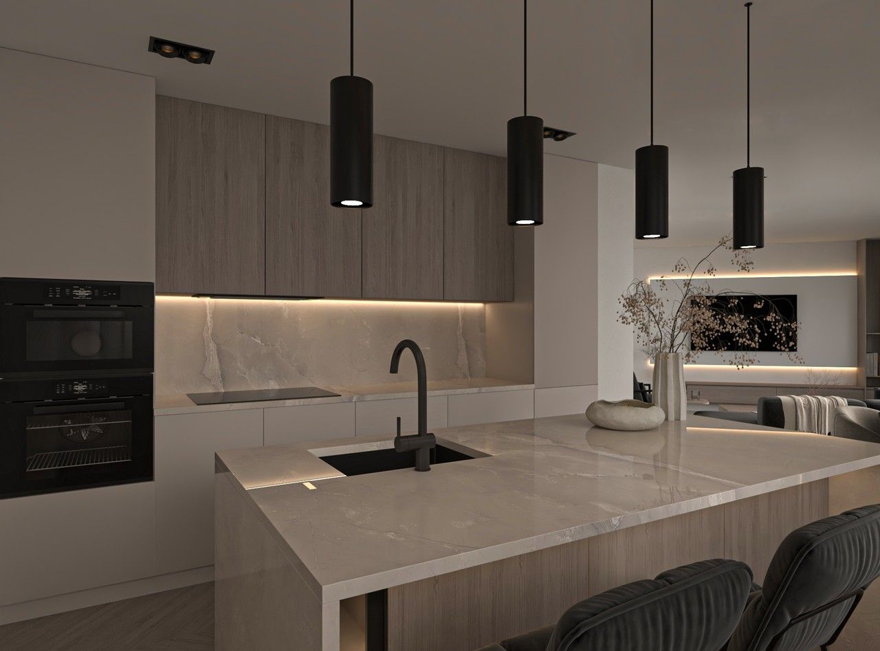 Vue rapprochée de la cuisine d’un appartement rénové à Liège, avec îlot central en pierre claire, évier noir, mobilier en bois clair et éclairage suspendu.
