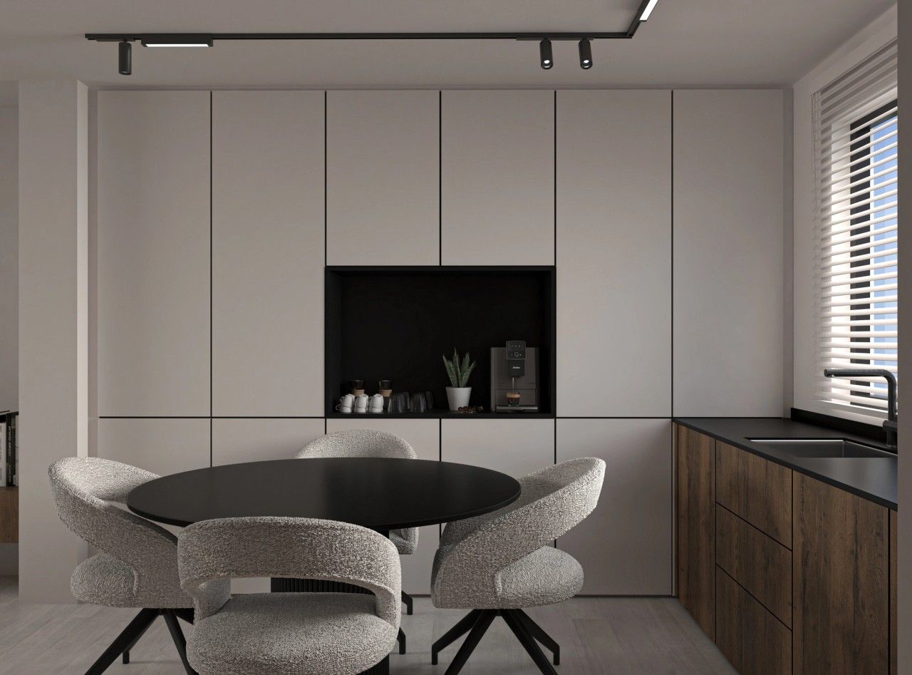 Vue rapprochée de l’espace repas dans la cuisine à Herstal, avec table ronde noire, fauteuils texturés et mobilier intégré toute hauteur.