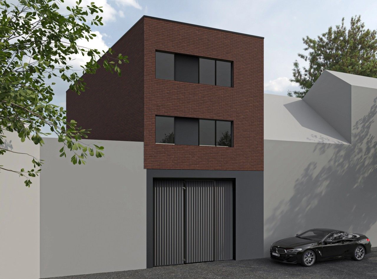 Façade avant d’un immeuble résidentiel à Grivegnée, avec parement en briques rouges, châssis anthracite et passage pompier intégré au rez-de-chaussée.