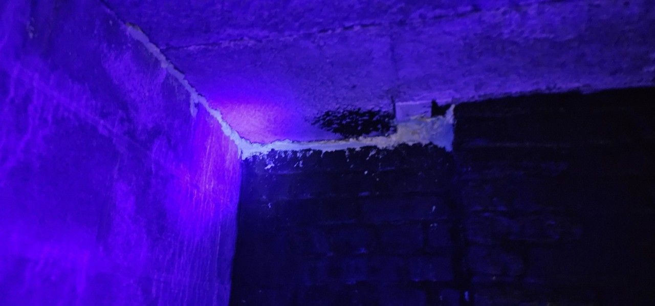Contrôle sous lumière ultraviolette d’une jonction entre mur et plafond à Ans lors d’un essai de traçage d’infiltration.