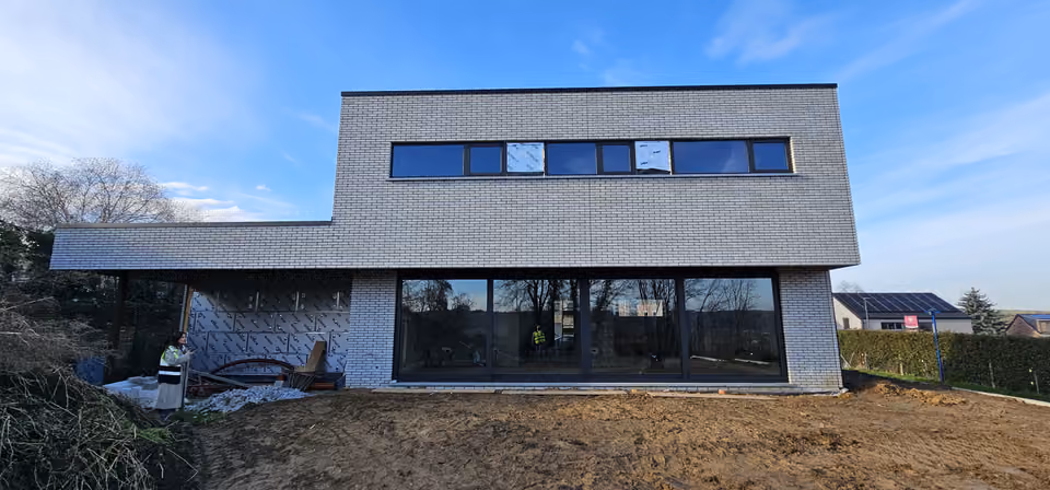 Maison en brique claire en chantier, les abords encore à aménager.