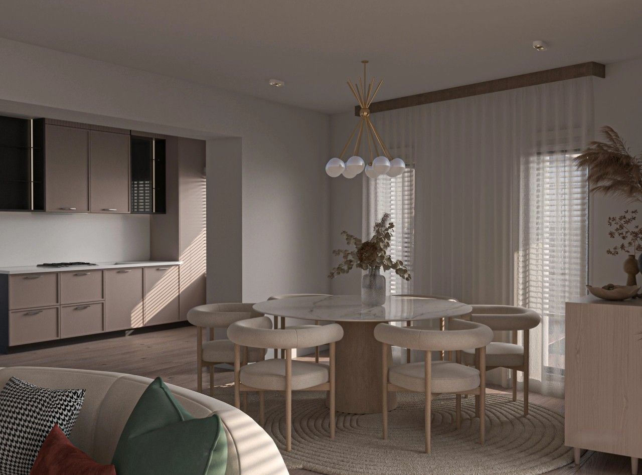 Vue intérieure de la salle à manger ouverte sur la cuisine d’un appartement rénové à Saint-Nicolas, avec table ronde, mobilier aux tons naturels, parquet en bois et grandes ouvertures filtrant la lumière.