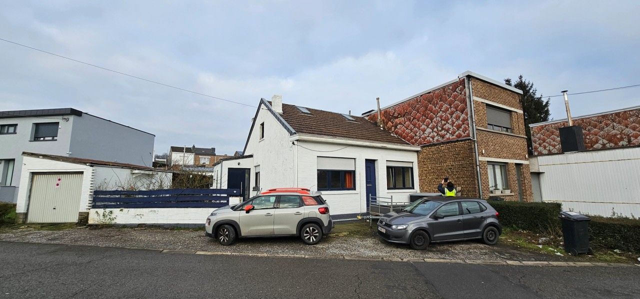 Maison unifamiliale existante à Herstal avant rénovation et surélévation, avec toiture inclinée et façade blanche sur rue.