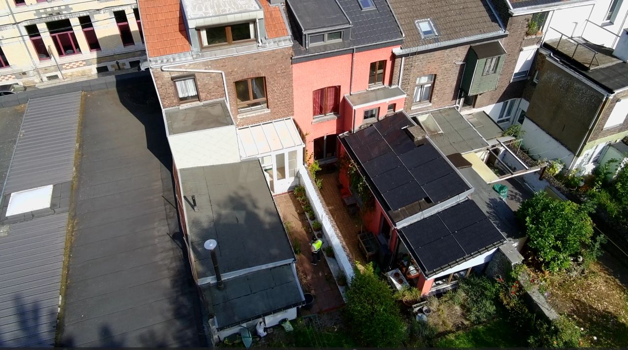 Vue aérienne de l’arrière d’une maison unifamiliale à Liège avant transformation, montrant les annexes existantes, la terrasse et le jardin enclavé entre les constructions voisines.