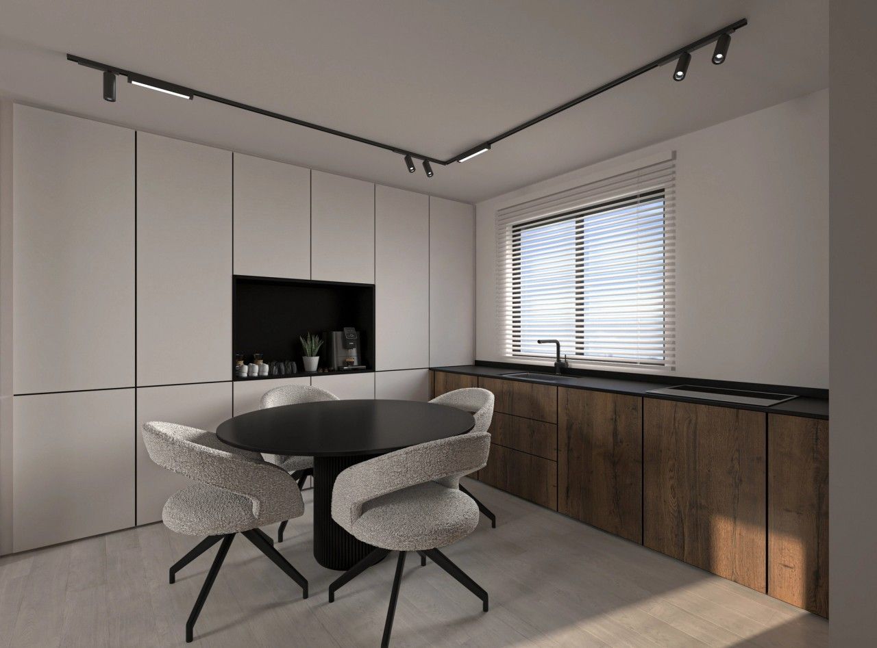 Vue de la cuisine sur mesure à Herstal, avec colonnes blanches, niche noire pour le café, façades basses en bois et grande fenêtre apportant la lumière naturelle.