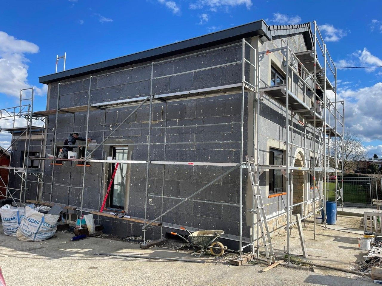 Pose de panneaux d’isolation thermique par l’extérieur sur la façade latérale d’une habitation en rénovation à Vottem.