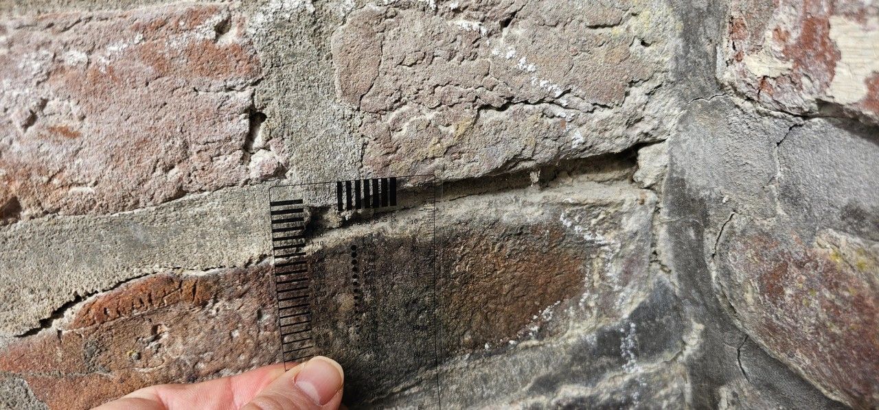 Mesure sur site de l’ouverture d’une fissure dans un joint de maçonnerie en briques à Beyne-Heusay à l’aide d’une jauge graduée.