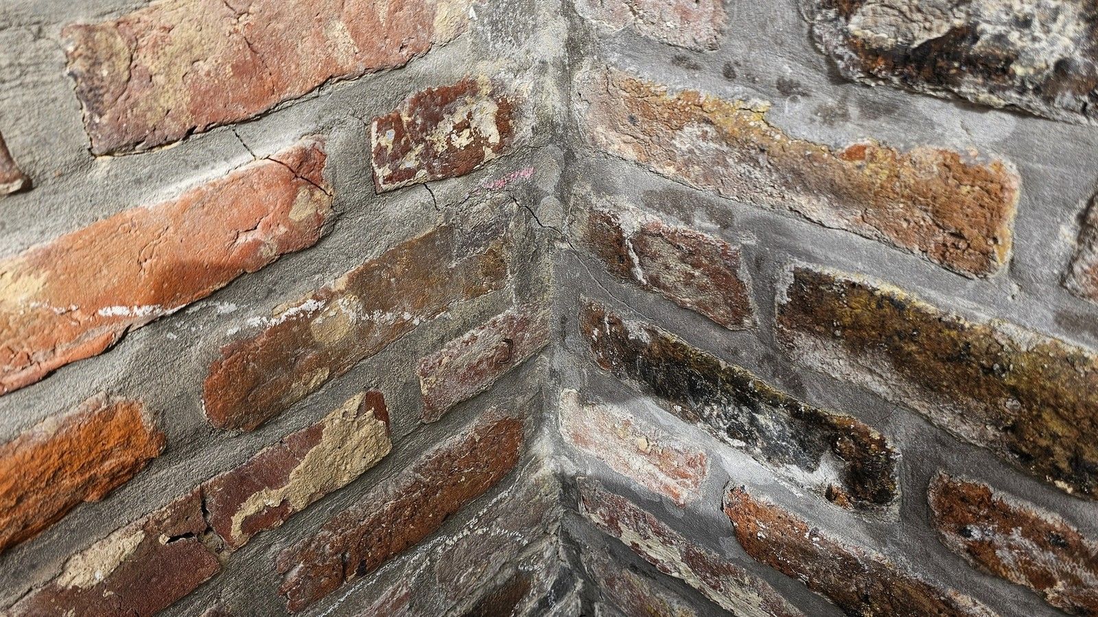 Vue rapprochée d’un angle de façade en briques à Beyne-Heusay présentant plusieurs fissures dans les joints de mortier et le parement.