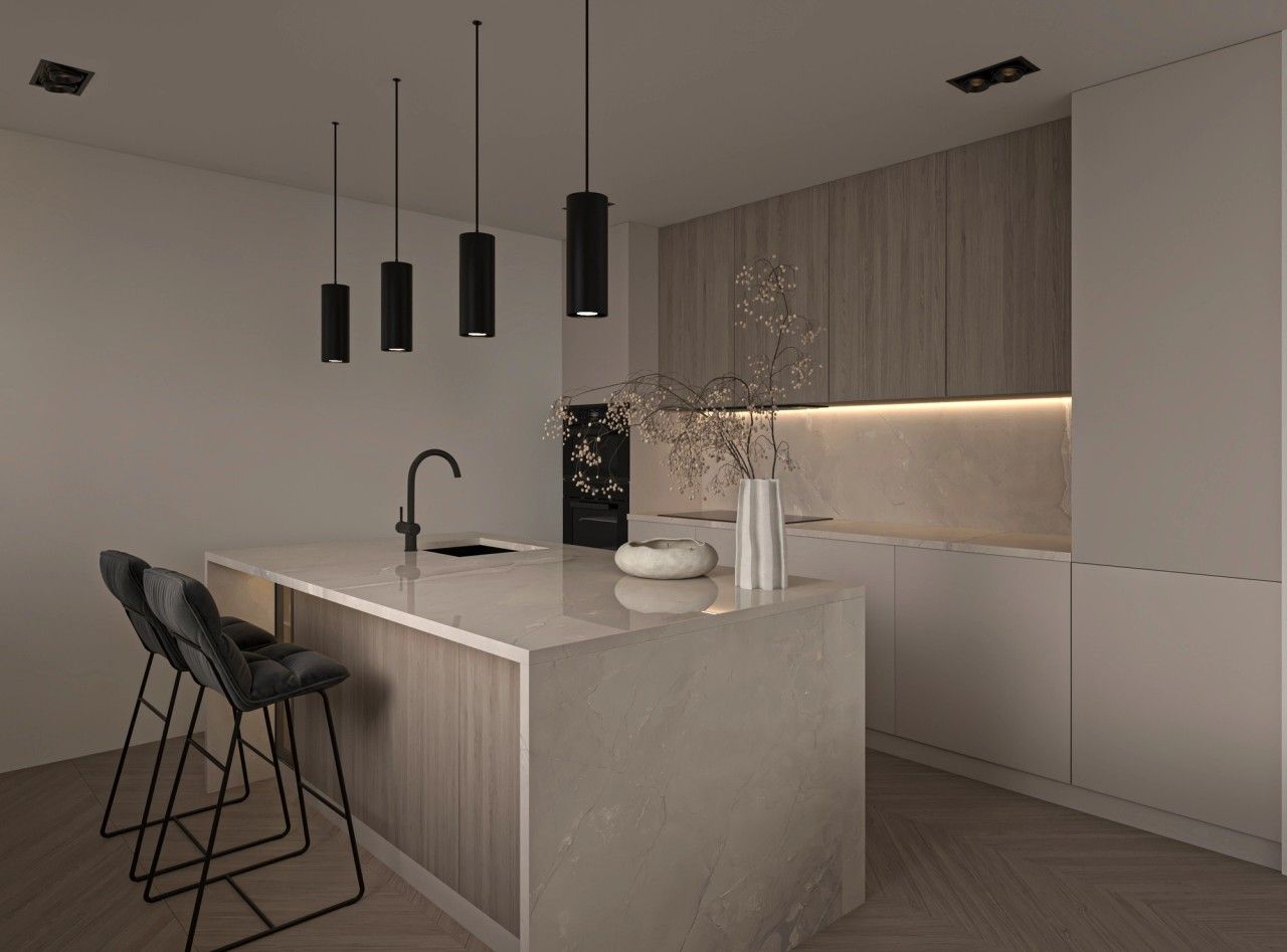 Cuisine contemporaine rénovée dans un appartement à Liège, avec grand îlot central en pierre claire, mobilier en bois clair, façades blanches et suspensions noires.