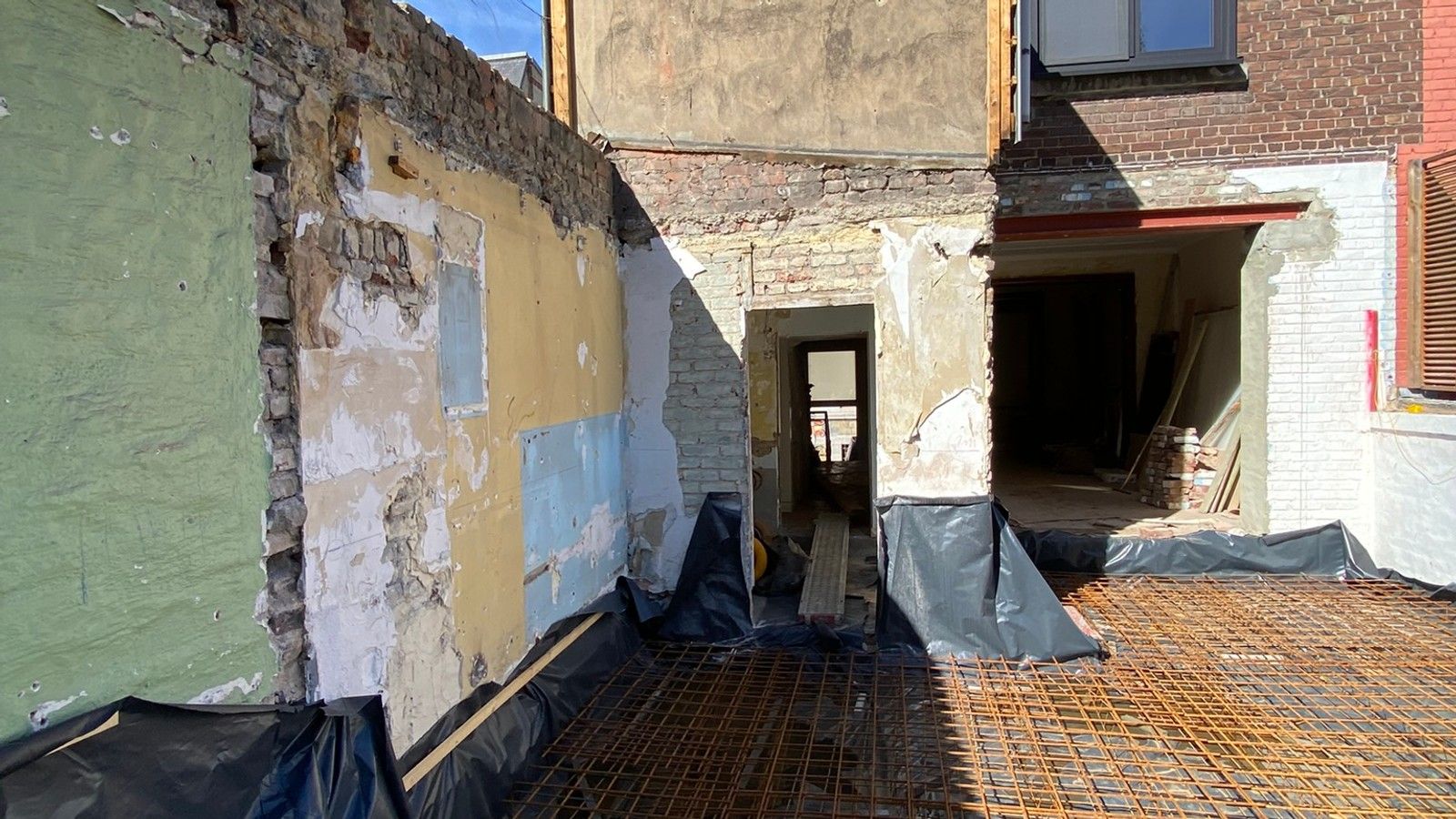Chantier d’extension d’une maison à Liège après démolition des anciennes annexes, avec préparation du radier et pose des armatures avant bétonnage.