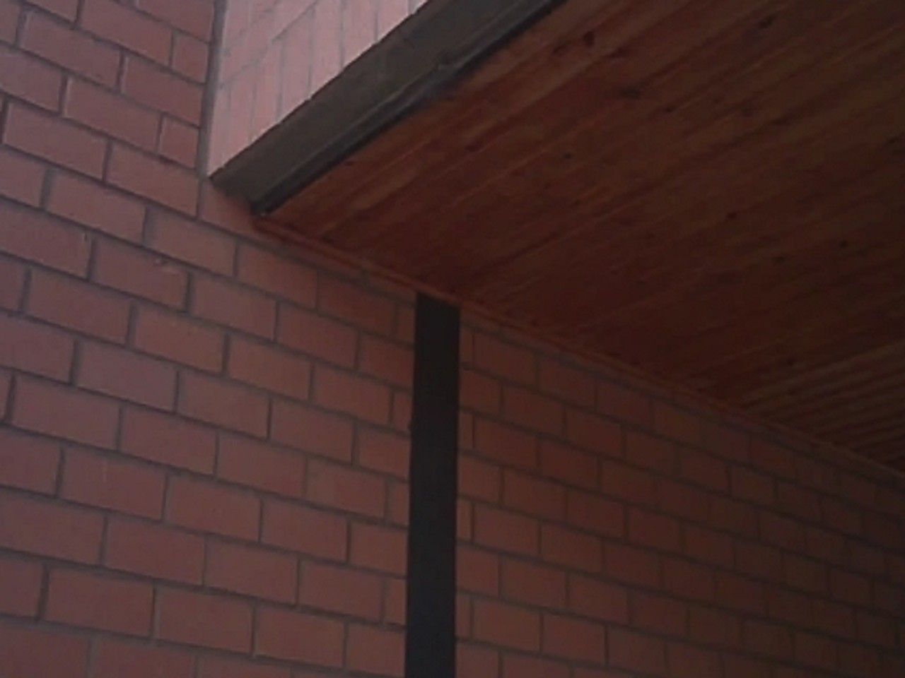 Vue extérieure d’un raccord entre façade en briques et débord de toiture à Ans, examiné lors de la recherche de l’origine d’une infiltration d’eau.