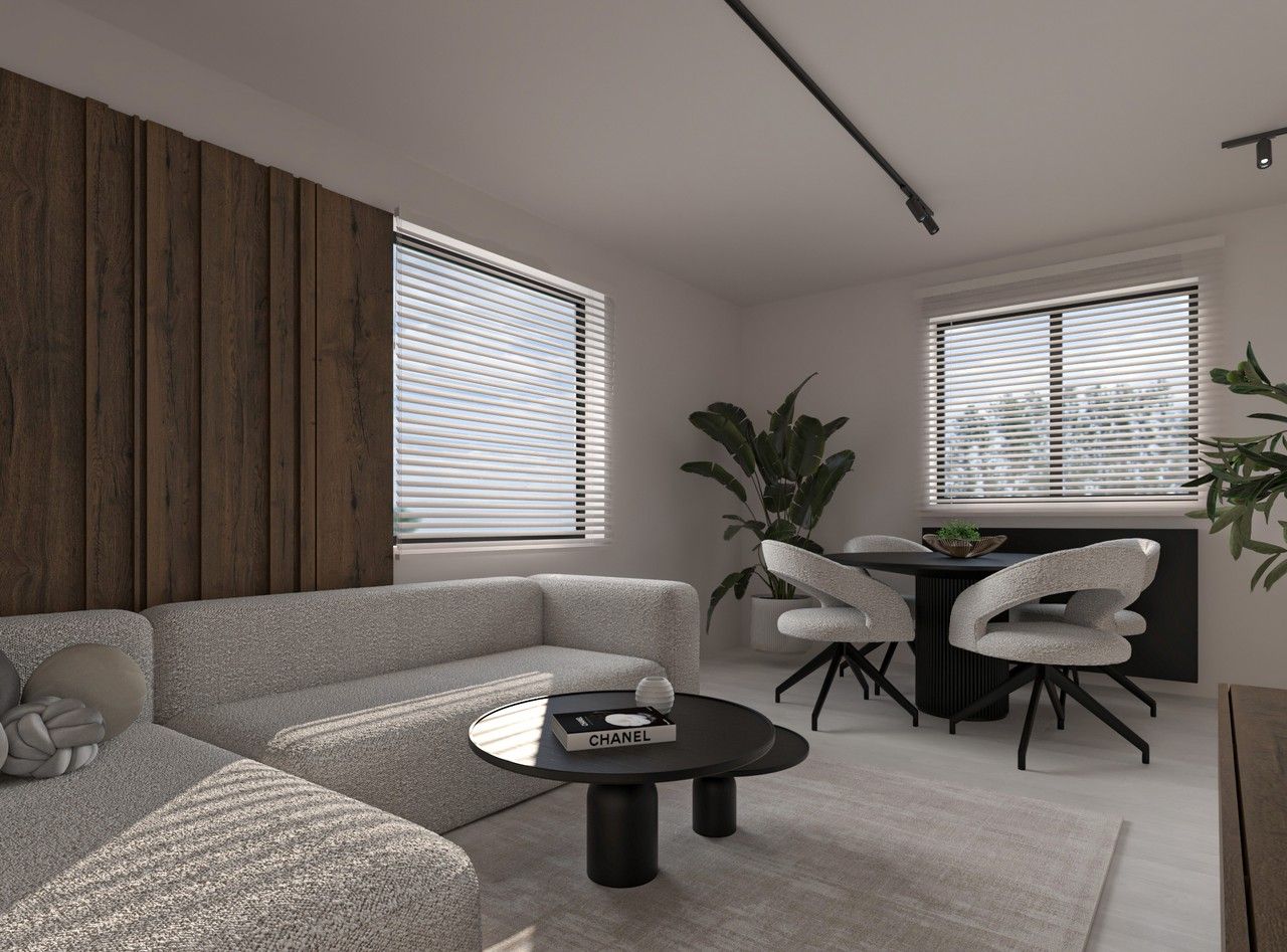 Vue de l’espace de vie à Herstal réunissant salon et salle à manger, avec mobilier clair, parement en bois et végétation intérieure.