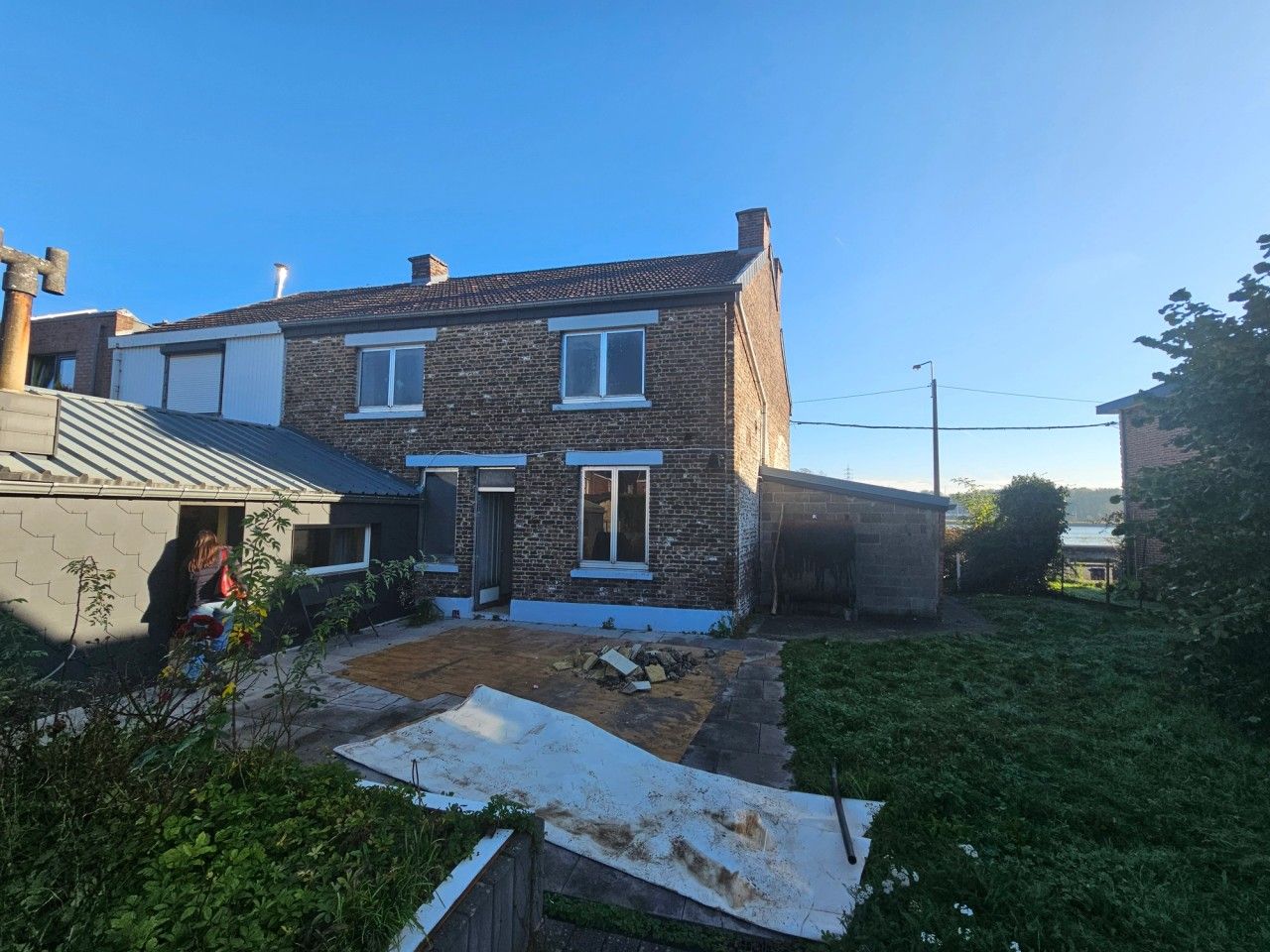 Vue générale de la façade arrière de la maison à Visé avant transformation, avec annexe basse et volumes secondaires autour du jardin.