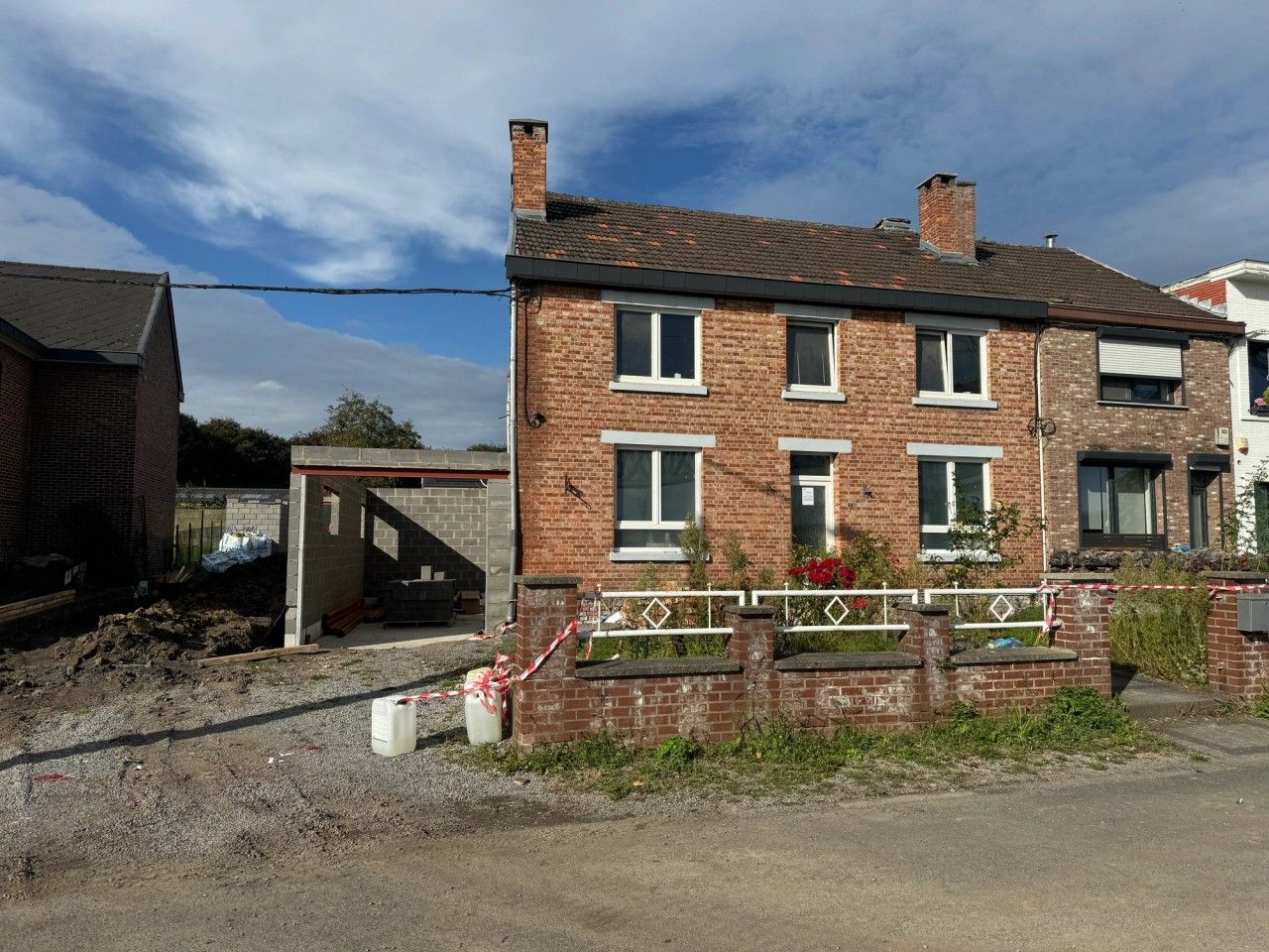 Vue depuis la rue de la maison à Visé pendant les travaux, avec nouveau volume latéral en maçonnerie accolé à l’habitation existante.
