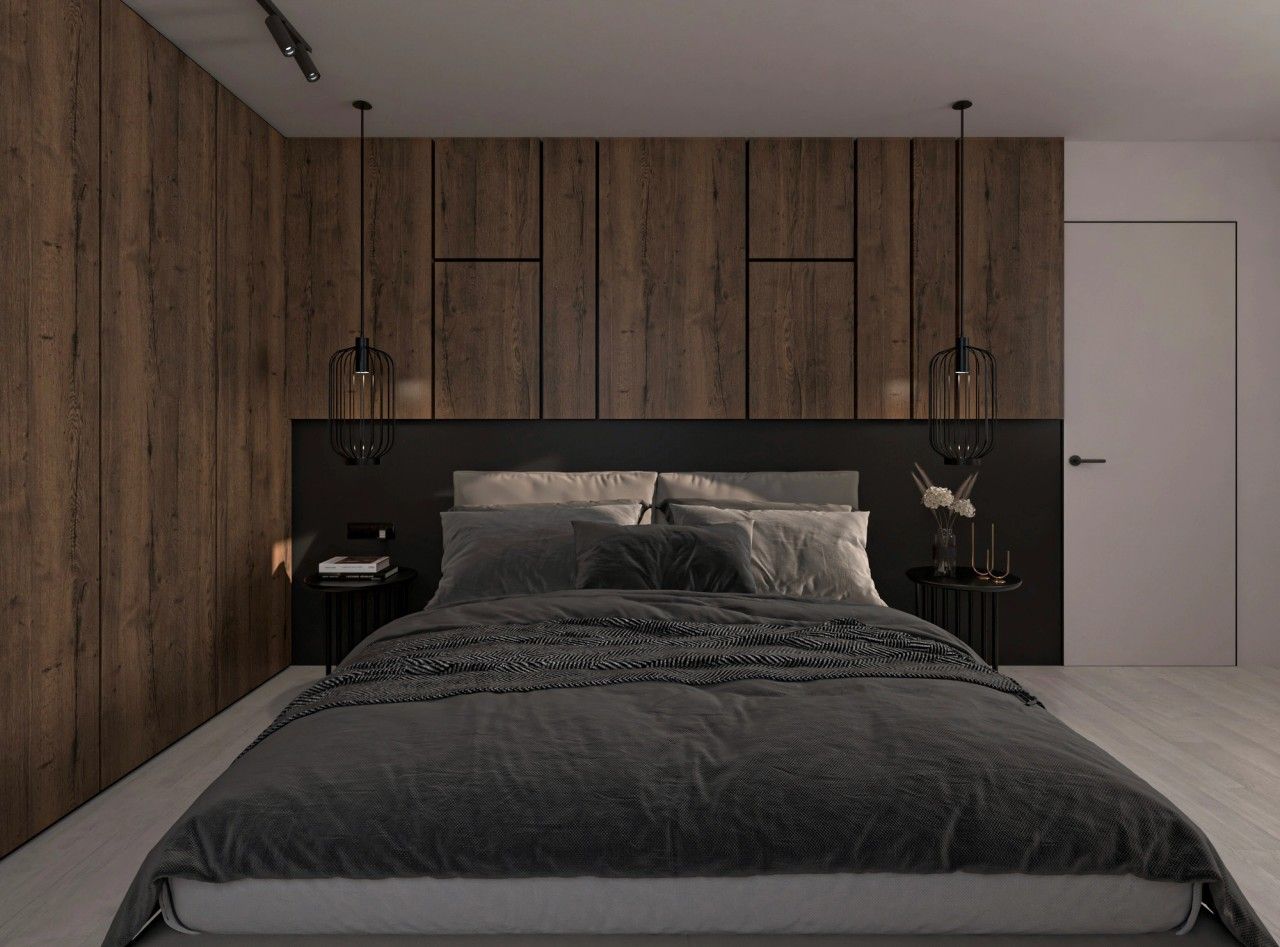 Vue de la chambre parentale à Herstal, avec tête de lit sombre, rangements intégrés en bois foncé et suspensions noires de part et d’autre du lit.