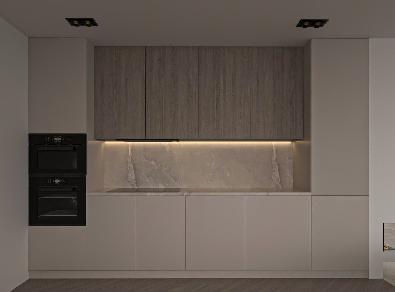 Vue frontale d’une cuisine contemporaine rénovée à Liège, avec rangements toute hauteur, façades en bois clair, mobilier blanc et crédence en pierre naturelle éclairée.